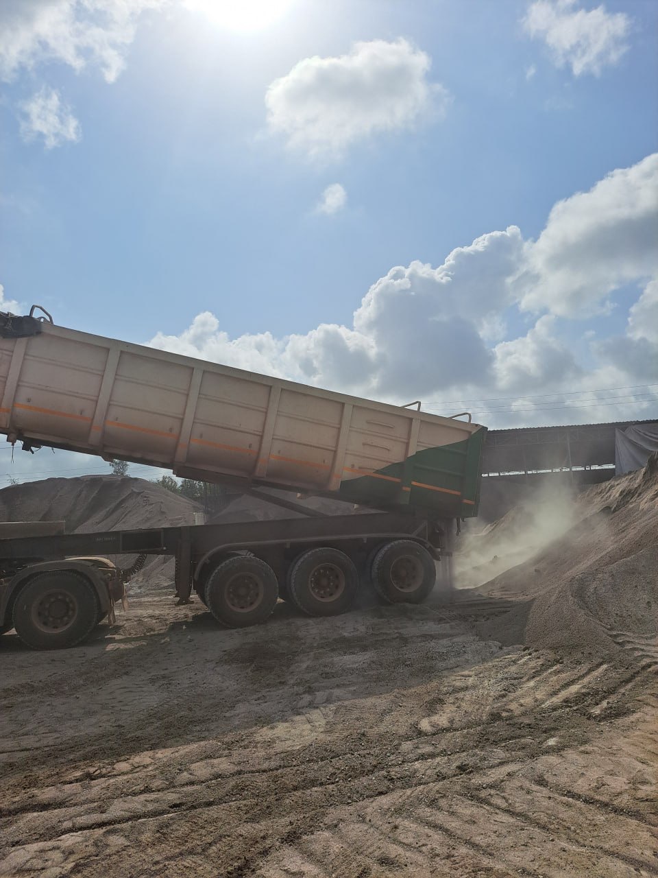 Trailer tipping a load of fine aggregate beside the crusher